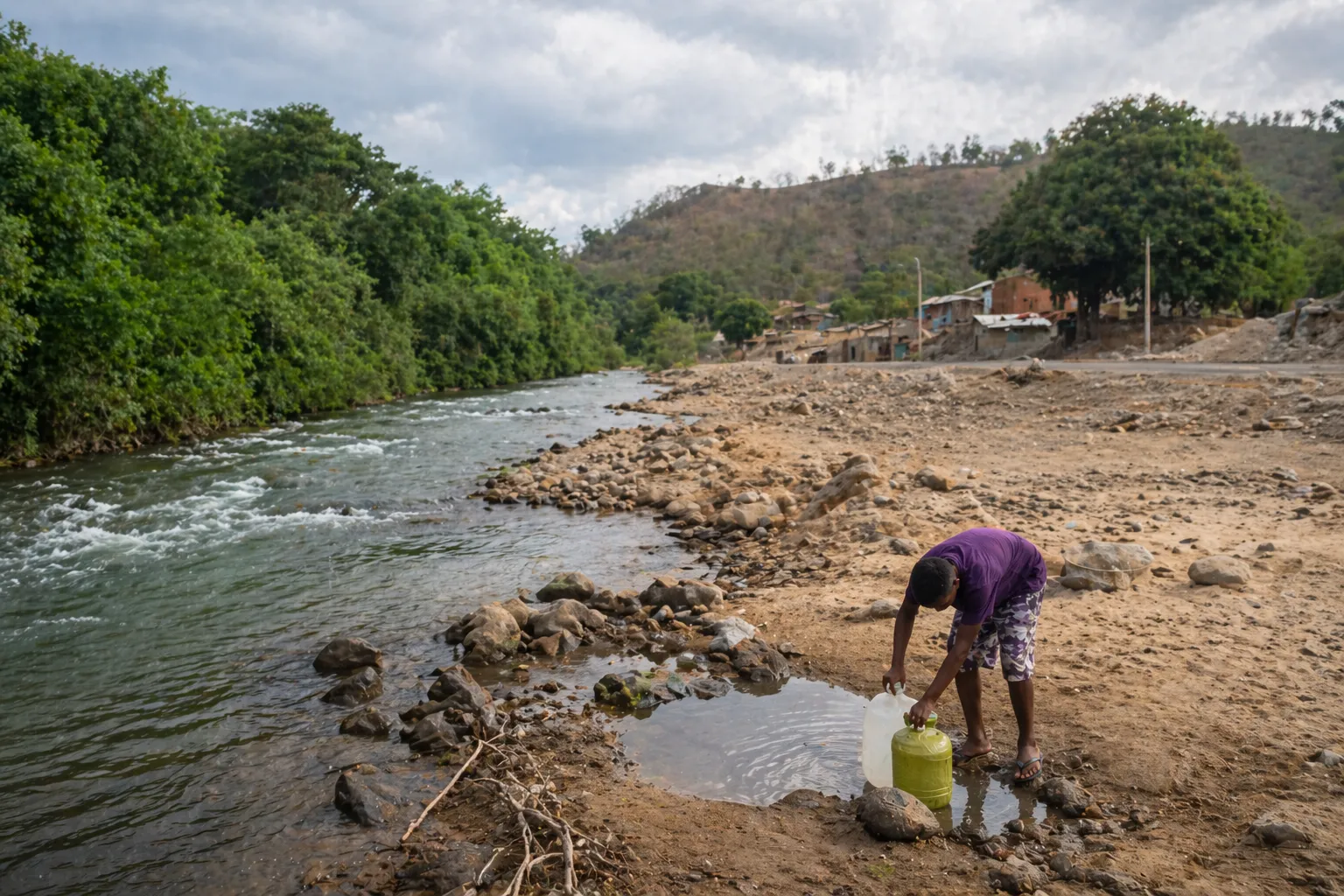 Persona recogiendo agua en un río en una zona vulnerable, evidenciando la desigualdad en el acceso al agua potable en Colombia.